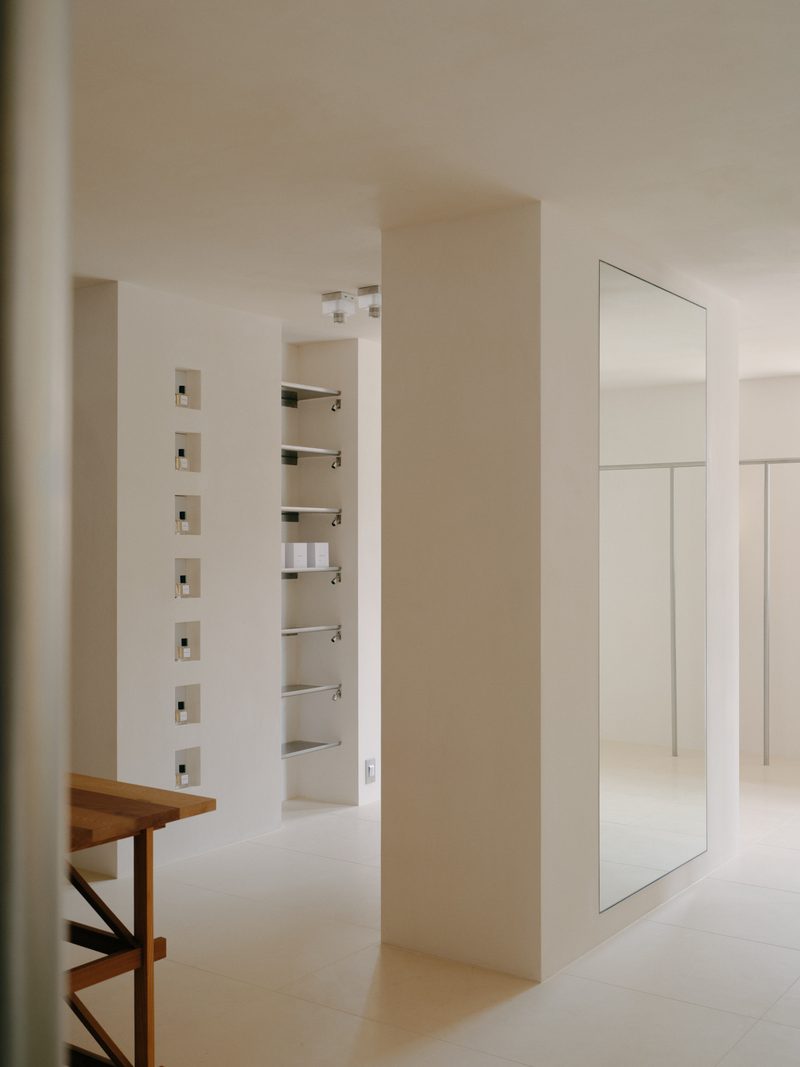 White dressing room with steel hooks and a stool